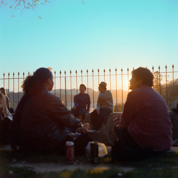 A group of adults enjoying a relaxed evening by the Porto riverside with a stunning sunset view.